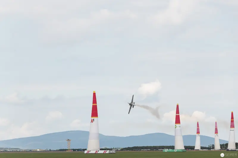 Red Bull Air Race Plane Navigating Precisely Between Vermilion Pylons Over Landscape