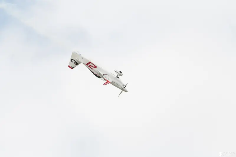 Red Bull Air Race Stunt Plane Executing Dramatic Aerial Maneuver Against Pale Sky
