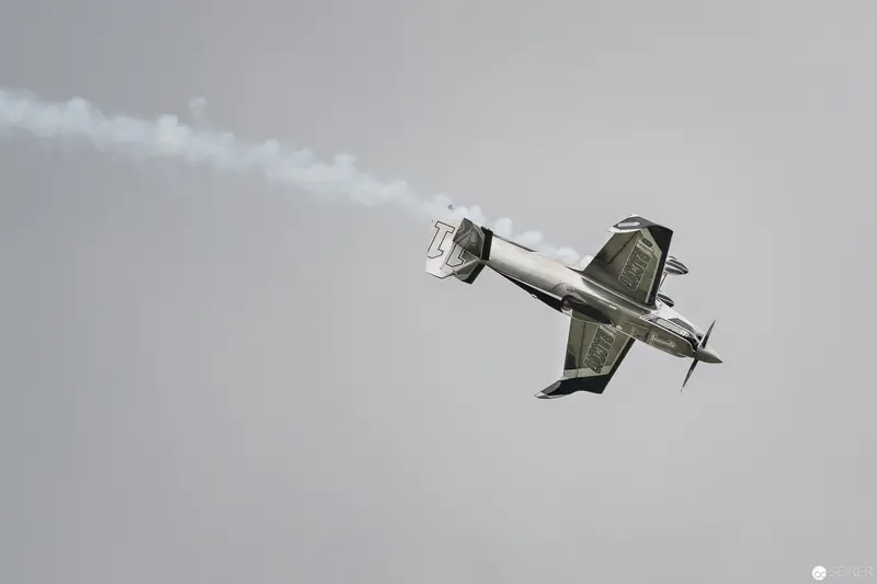 Red Bull Air Race Aerobatic Plane Executing Precise Inverted Maneuver Against Overcast Sky