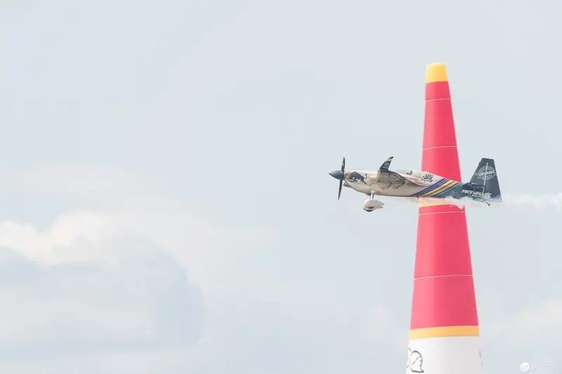 Red Bull Air Race Plane Navigating Crimson Pylon Against Pale Sky Backdrop