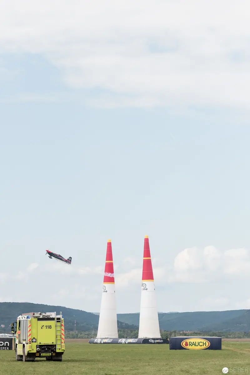 Red Bull Air Race: Aerial Competitor Navigating Pylons Near Support Vehicle