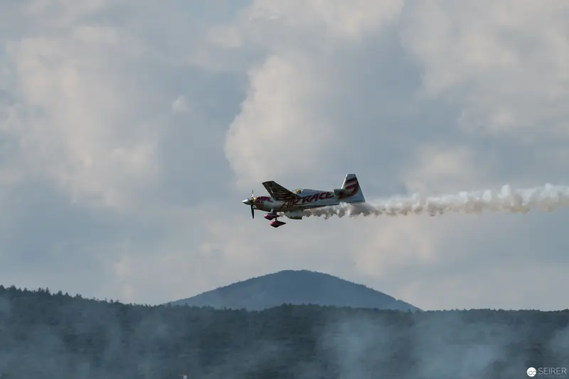 Red Bull Air Race Aerobatic Performance Over Mountainous Forested Landscape