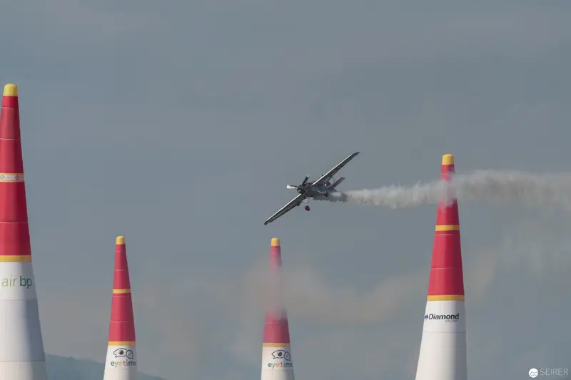 Red Bull Air Race: Precision Aircraft Navigating Crimson Pylons Against Overcast Sky