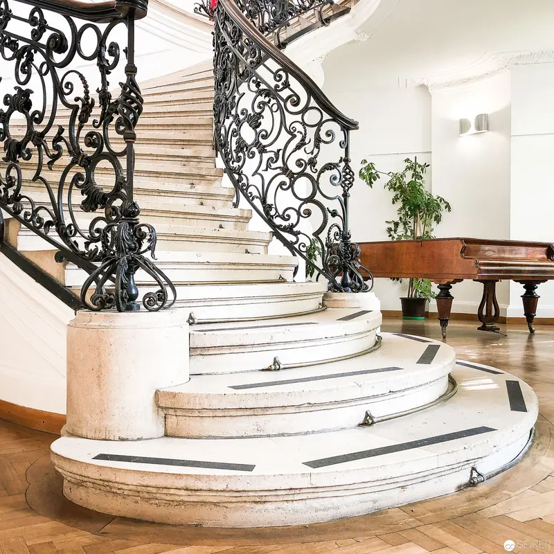 Ornate Marble Staircase with Intricate Wrought-Iron Railings in Elegant Interior
