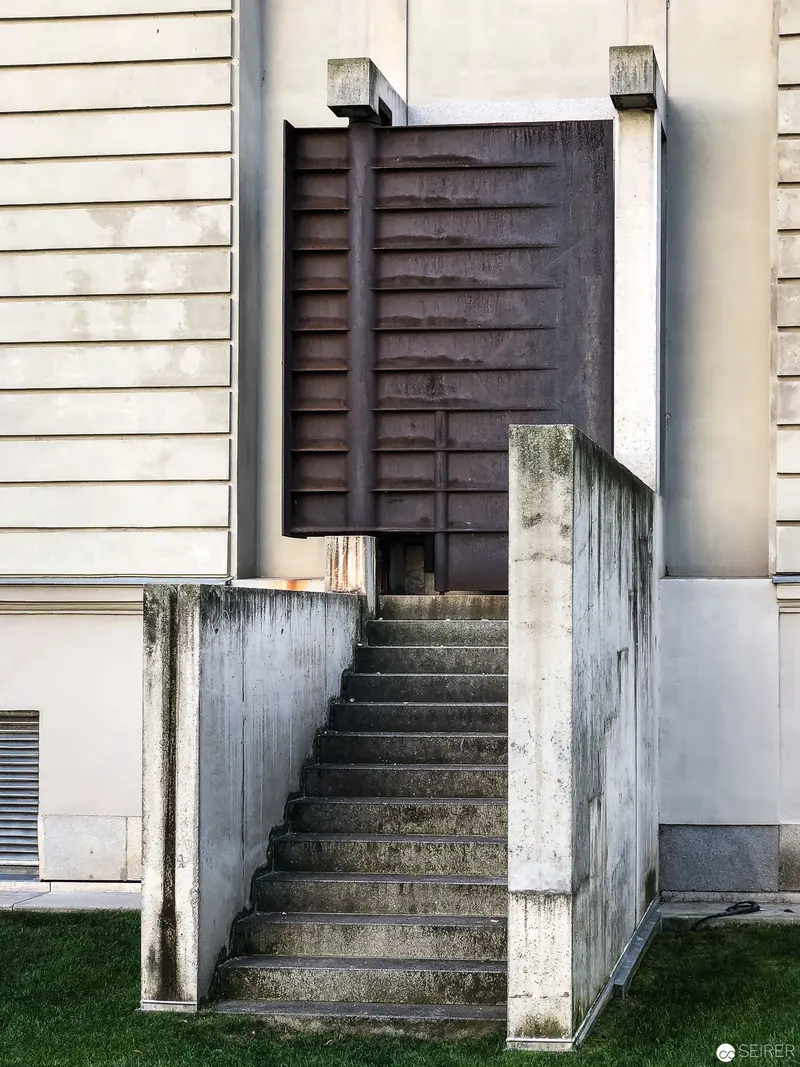 Concrete Staircase with Dark Wooden Shuttered Entrance at Architectural Site