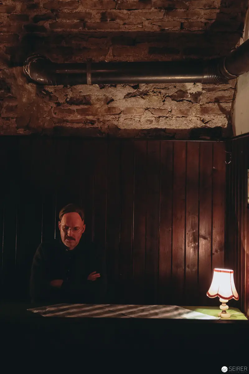 Nesterval Theater Performance "Das Dorf": Solitary Figure in Dimly Lit Interior