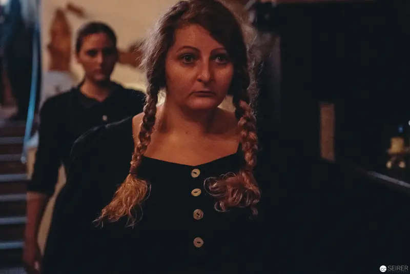 Nesterval Theater Performance "Das Dorf": Woman in Black with Braided Hair