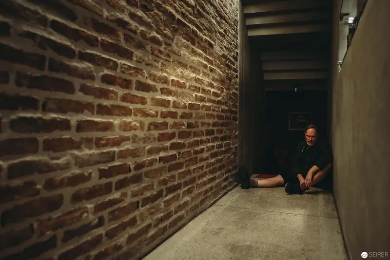 Nesterval Theatre Performance "Das Dorf": Solitary Figure in Confined Brick Passageway