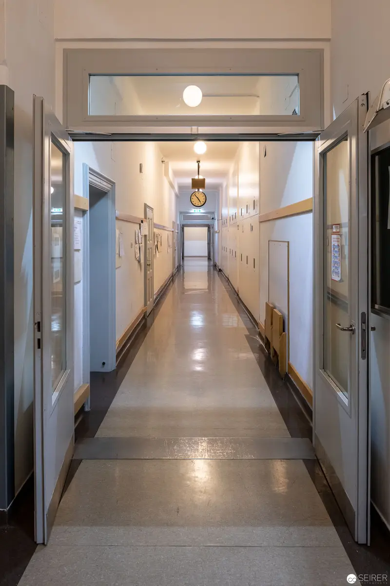 Institutional Interior: Luminous Corridor with Symmetrical Doors and Polished Floor