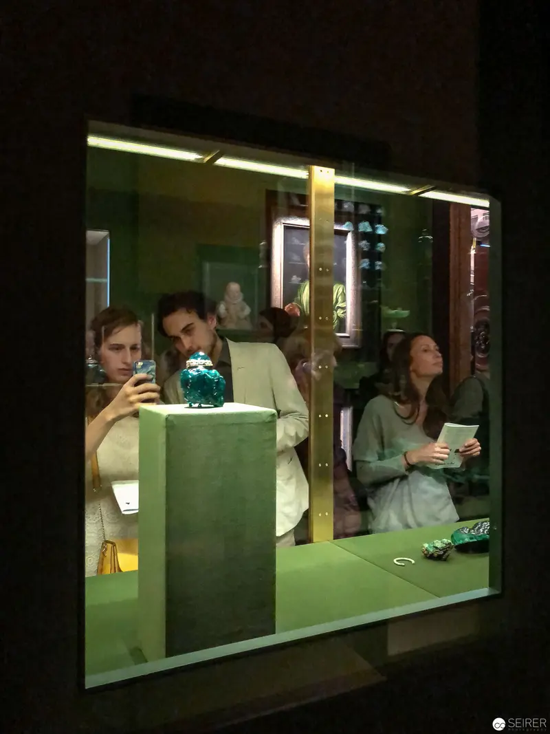 Museum Exhibition Viewers Reflected in Green-Tinted Display Window