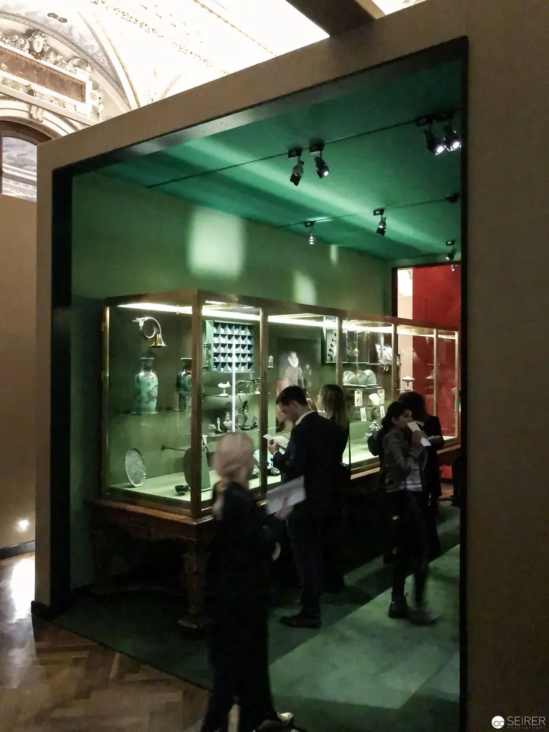 Museum Display with Green Illumination and Visitor Silhouettes