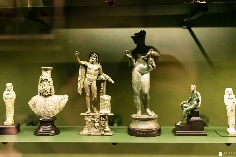 Classical Statuettes Displayed in Muted Green Museum Setting