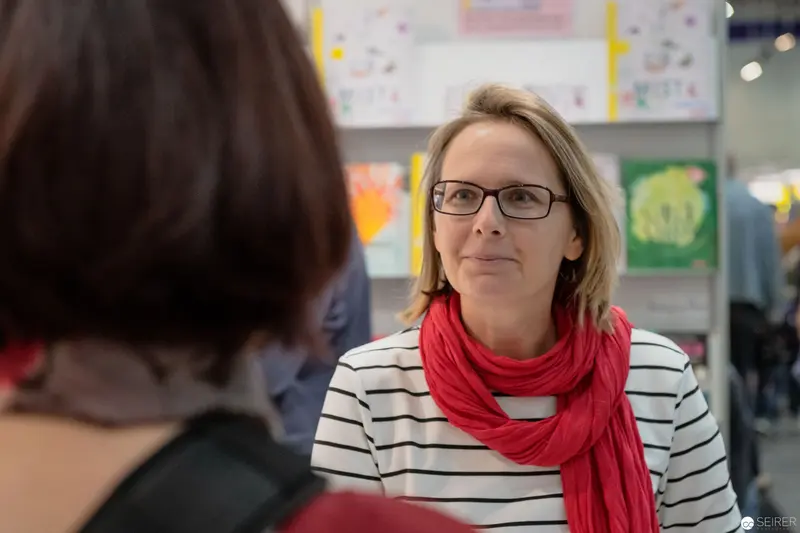 Janett Cernohuby in Conversation at Buch Wien Event with Striped Top and Red Scarf