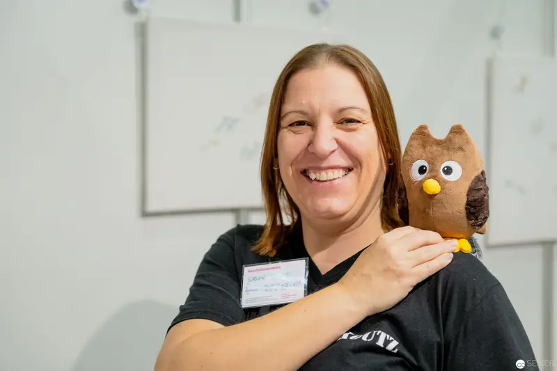 Cheerful Professional with Whimsical Owl Mascot at Workplace Event
