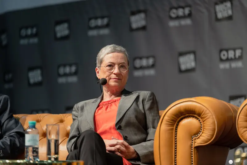 Janett Cernohuby Speaking at ORF Media Event in Thoughtful Seated Pose