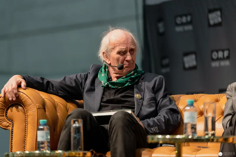 Distinguished Elder at Public Panel Discussion in Leather Chair with Green Scarf