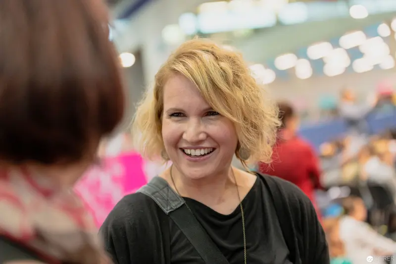 Joyful Woman Radiating Warmth at Buch Wien Event with Blurred Background