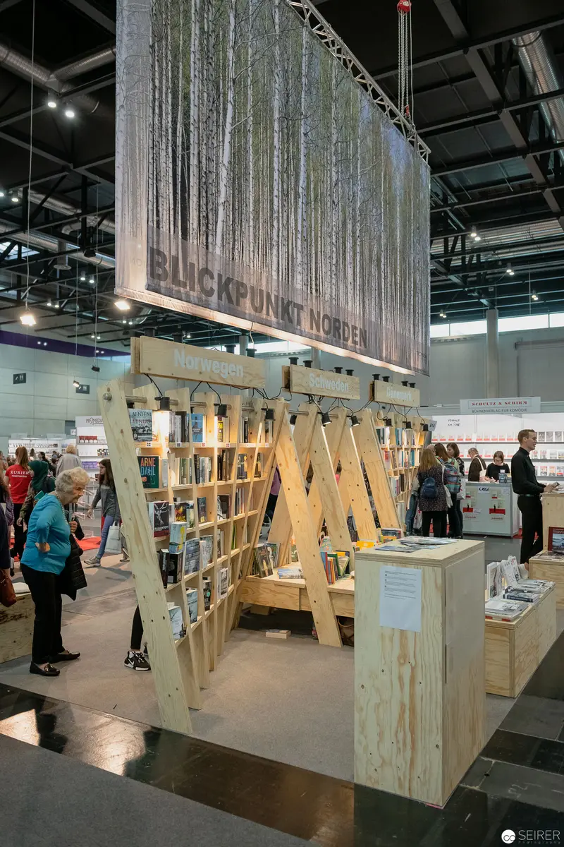 Buch Wien Exhibition: Wooden Lattice Display with Suspended Forest Backdrop