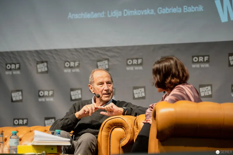 ORF Event Panel Discussion with Elderly Participant in Leather Chair