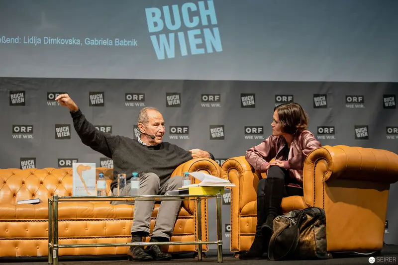 Buch Wien Literary Event: Authors Engaged in Animated Conversation on Yellow Leather Furniture