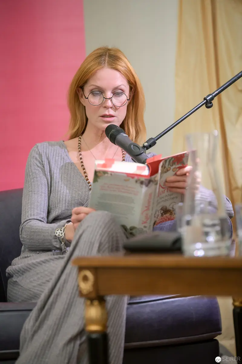 Kate Morton Reading "Die Tochter des Uhrmachers" at Literary Event with Microphone