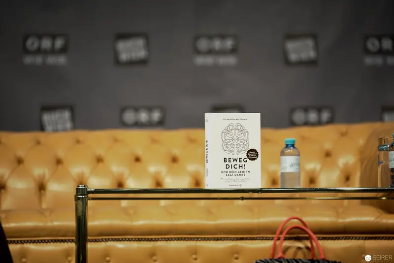 Book and Water Bottle on Tufted Yellow Leather Couch at Press Event