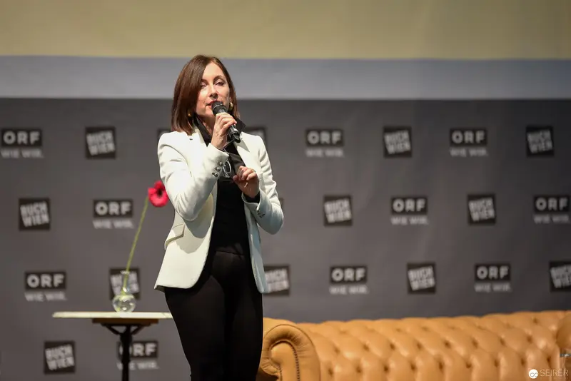 ORF Event Speaker in White Blazer Presenting on Staged Platform