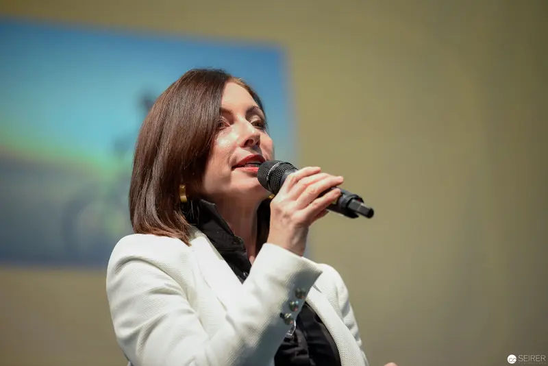 Speaker in White Blazer Delivers Passionate Address at Podium