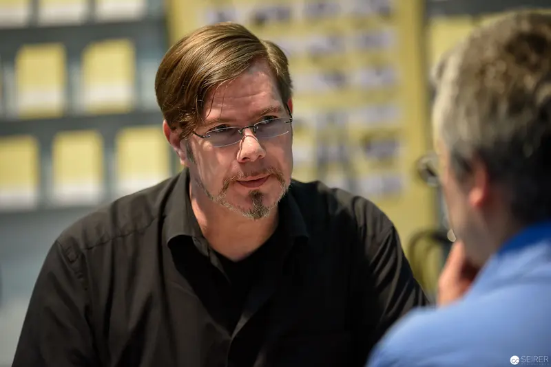 Contemplative Professional in Black Shirt During Workplace Discussion