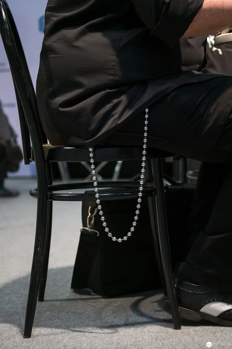 Black Suit and Pearl Necklace: Seated Moment in Monochromatic Setting