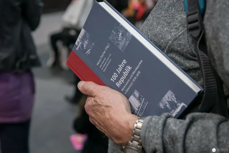 Hand Holding Historical Reference Book in Gray-Toned Urban Setting