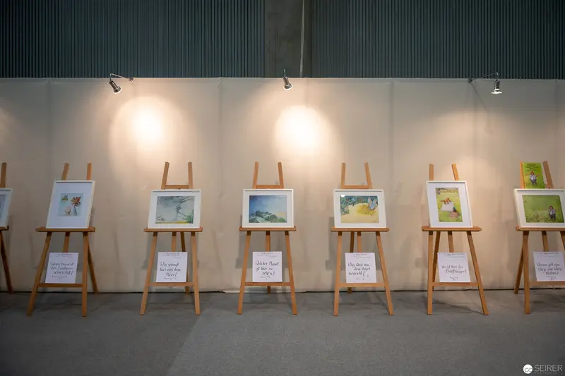 Art Exhibition Showcasing Six Framed Paintings on Wooden Easels