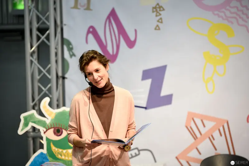 Presenter at Literary Event with Colorful Graphic Backdrop