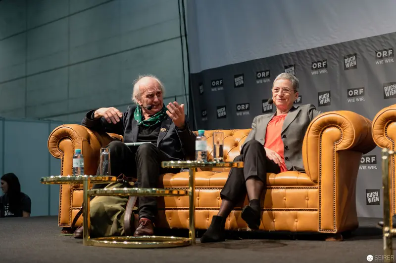 Two Elderly Speakers at ORF Media Event in Leather Armchair Setting