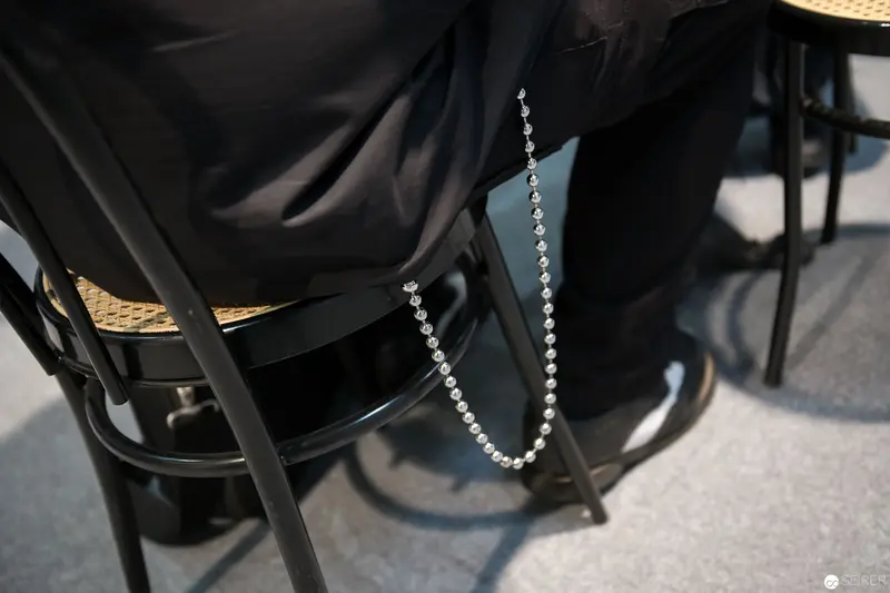 Delicate Silver Chain Draped Over Black Fabric and Woven Chair