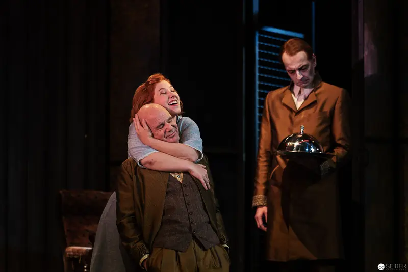 Lakrimosa and Vetter Embrace amid Theatrical Staging with Lurking Servant