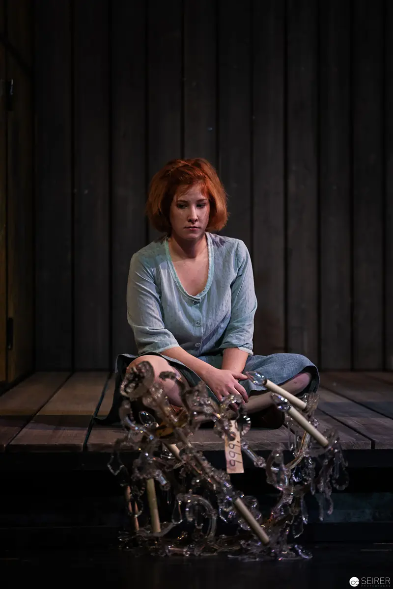Contemplative Woman with Intricate Mechanical Sculpture in Shadowy Studio Setting