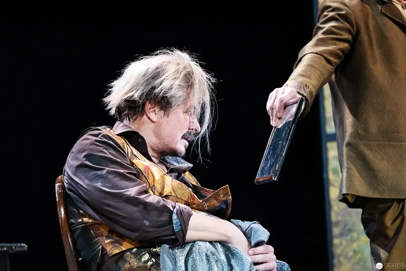 Fortunatus Wurzel Seated in Contemplative Pose During Theatrical Performance