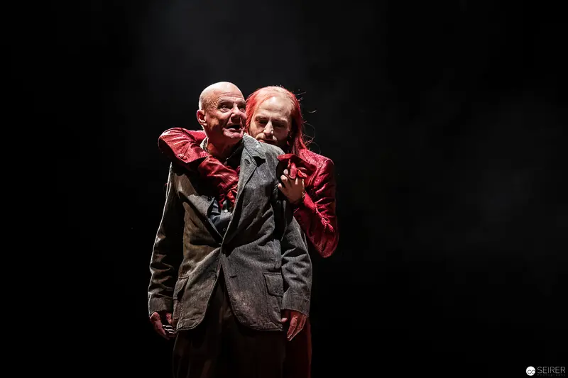 Two Male Performers in Dark Stage Setting with Dramatic Red Costume Accent