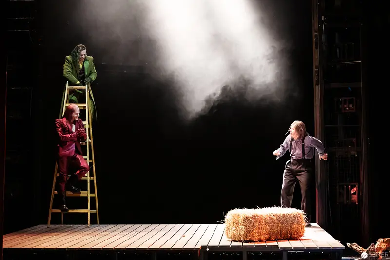 Lakrimosa's Theatrical Scene: Performers on Ladder and Hay Bale in Dramatic Staging