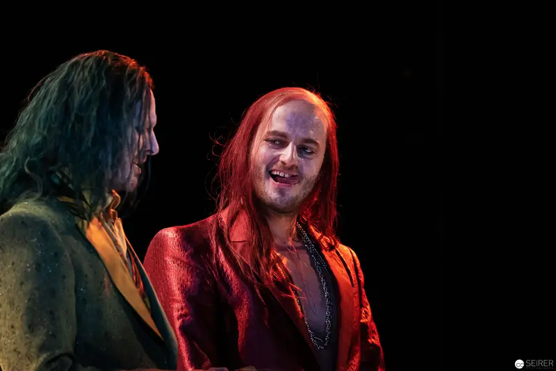 Two Theatrical Figures in Dramatic Red and Green Stage Lighting