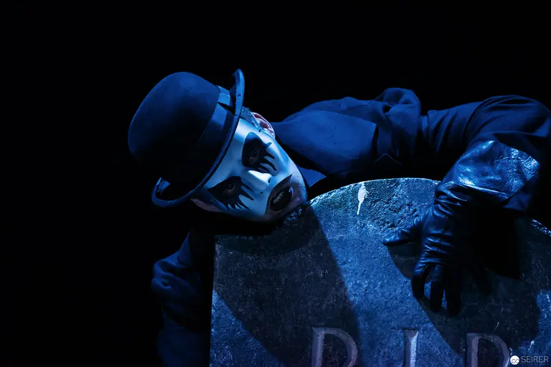 Lakrimosa Figure in Blue Reclining Against Gravestone in Dramatic Theatrical Scene