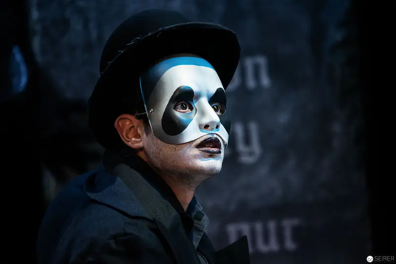 Theatrical Performer in Dramatic Blue-White Mask and Black Hat