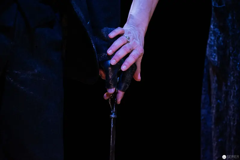 Intimate Hand Gesture Revealing Delicate Ring Against Dark Theatrical Backdrop