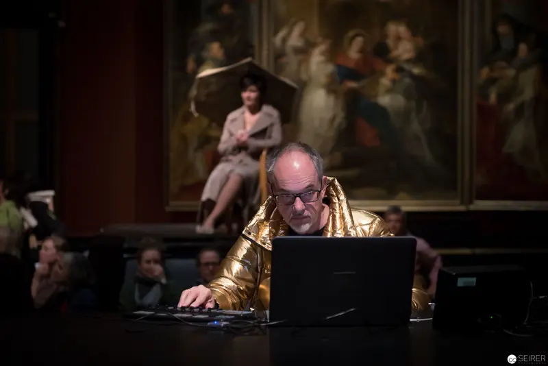 Gold-Jacketed Performer Working on Laptop during Ganymed Performance at KHM