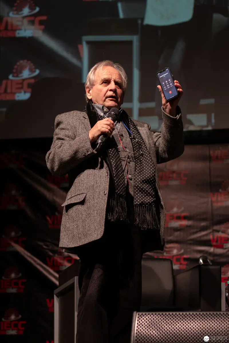 Sylvester McCoy Presenting at 2018 Vienna ComicCon with Microphone and Blue Object