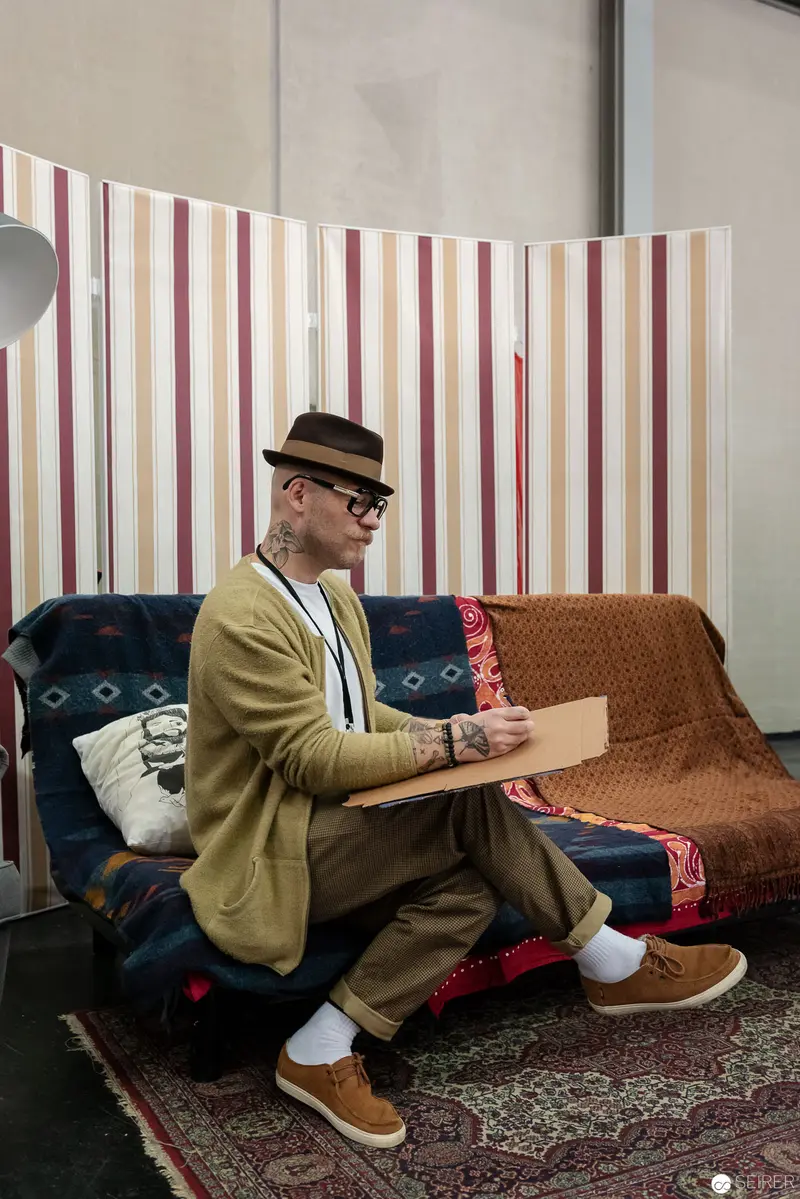 Spectacled Artist in Mustard Jacket Sketching at Vienna ComicCon 2018