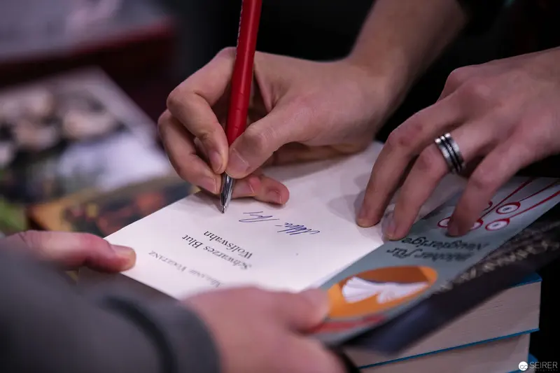 Book Signing Moment: Detailed Handwriting with Red Pencil and Open Literature
