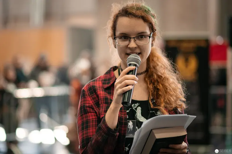 Speaker in Plaid Presenting at Vienna ComicCon 2018 with Microphone and Intensity