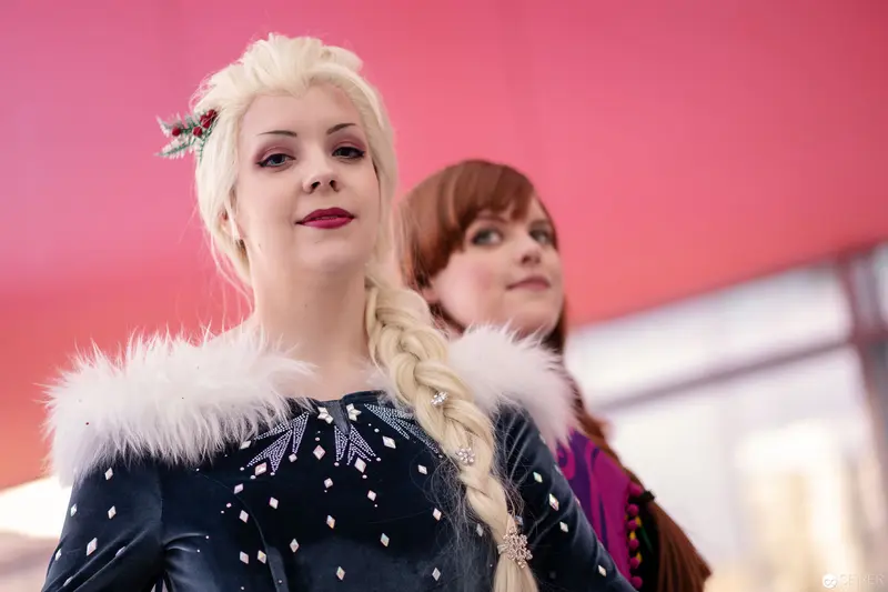 Vienna ComicCon 2018: Cosplay Performers in Fur-Trimmed Costumes Against Pink Background